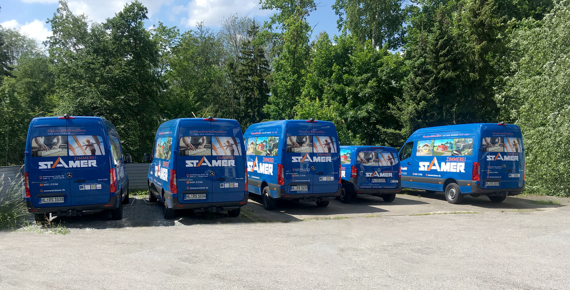 Fünf Stamer-Lieferwagen auf Parkplatz vor Bäumen