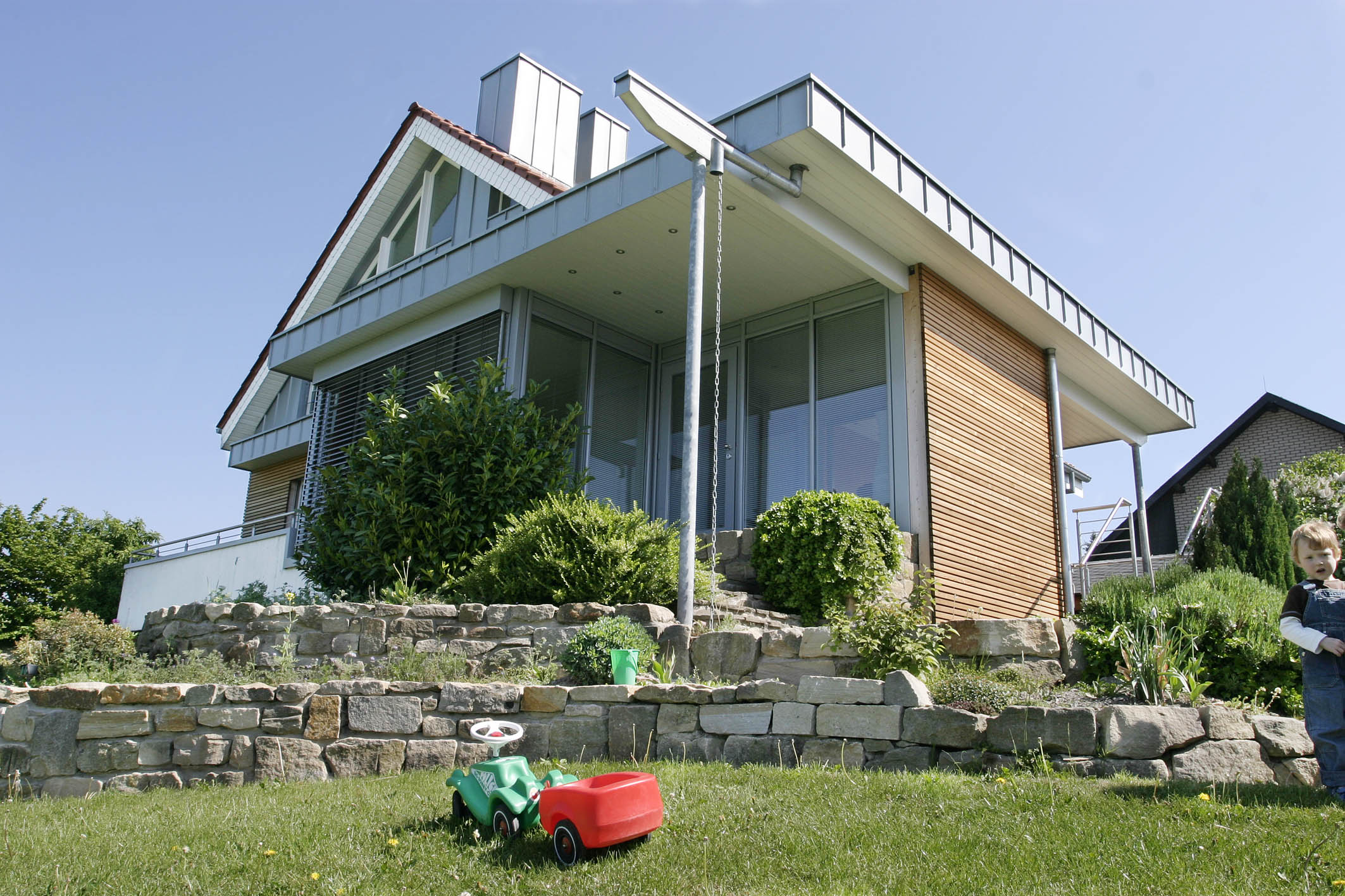 Einfamilienhaus am Hang mit Holzfassade und Natursteinmauern