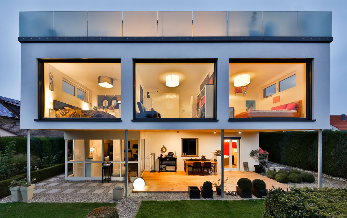 Modernes Wohnhaus mit großen Fensterfronten bei Dämmerung